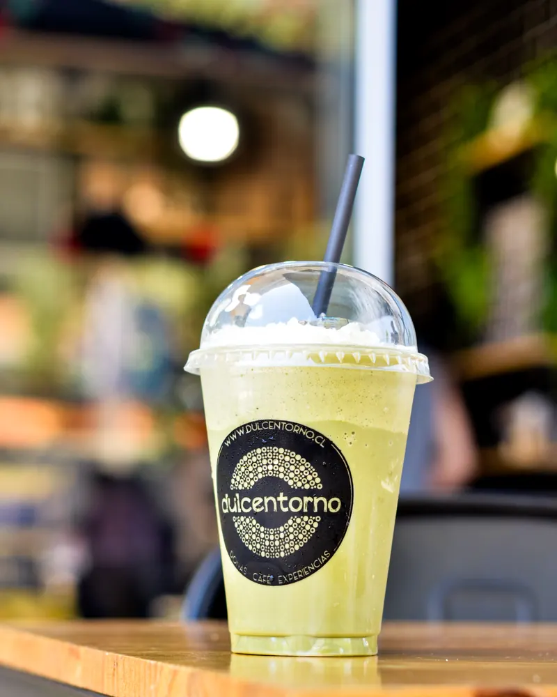 Batido verde con crema en vaso Dulcentorno, sobre una mesa de madera