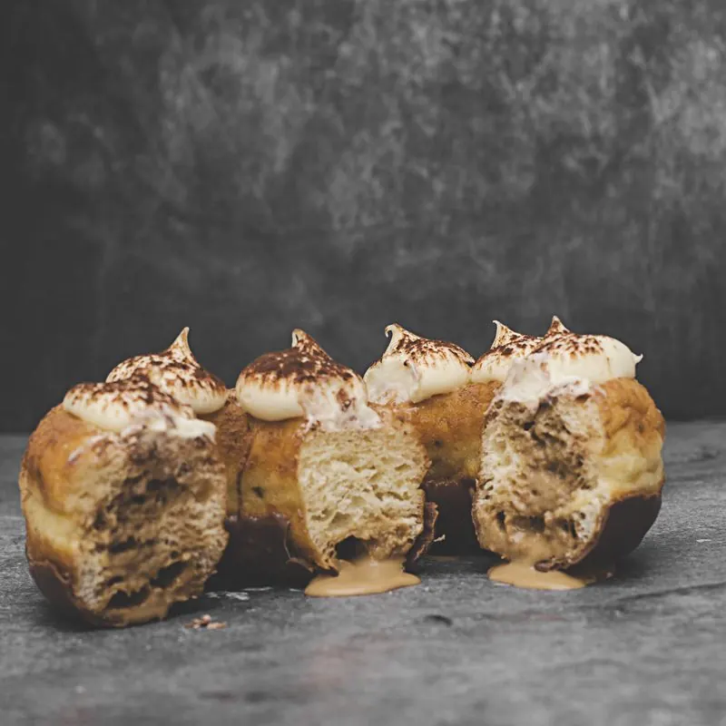 Cuatro donas con merengue y cacao, cortadas por la mitad: se ve el relleno cremoso