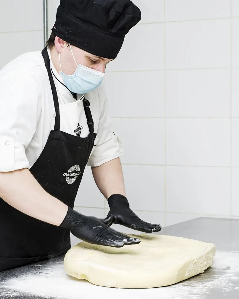 Persona del equipo trabajando a mano la masa brioche sobre el mesón enharinado
